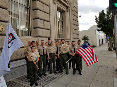 Sheriff Villanueva pictured next to deputies holding up flags