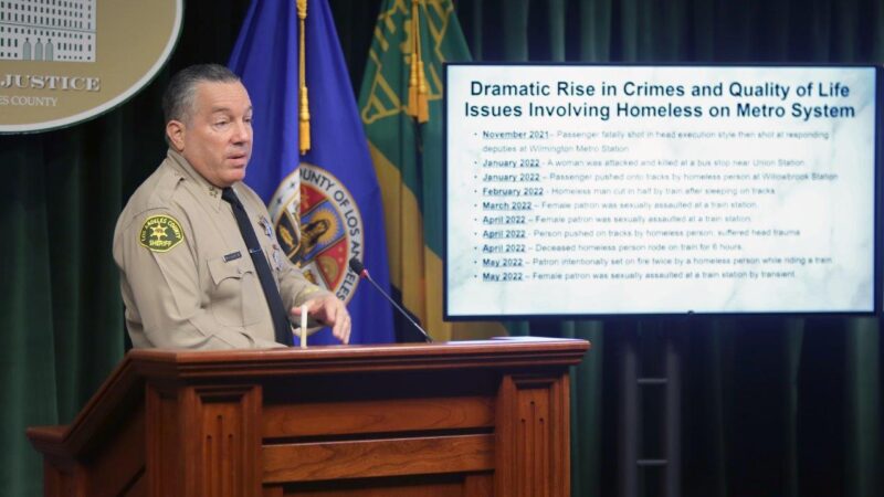 Sheriff Villanueva is standing at a podium infront of a TV that reads. "Dramatic Rise in crimes. Quality of life issues involving homlessnes on the Metro.