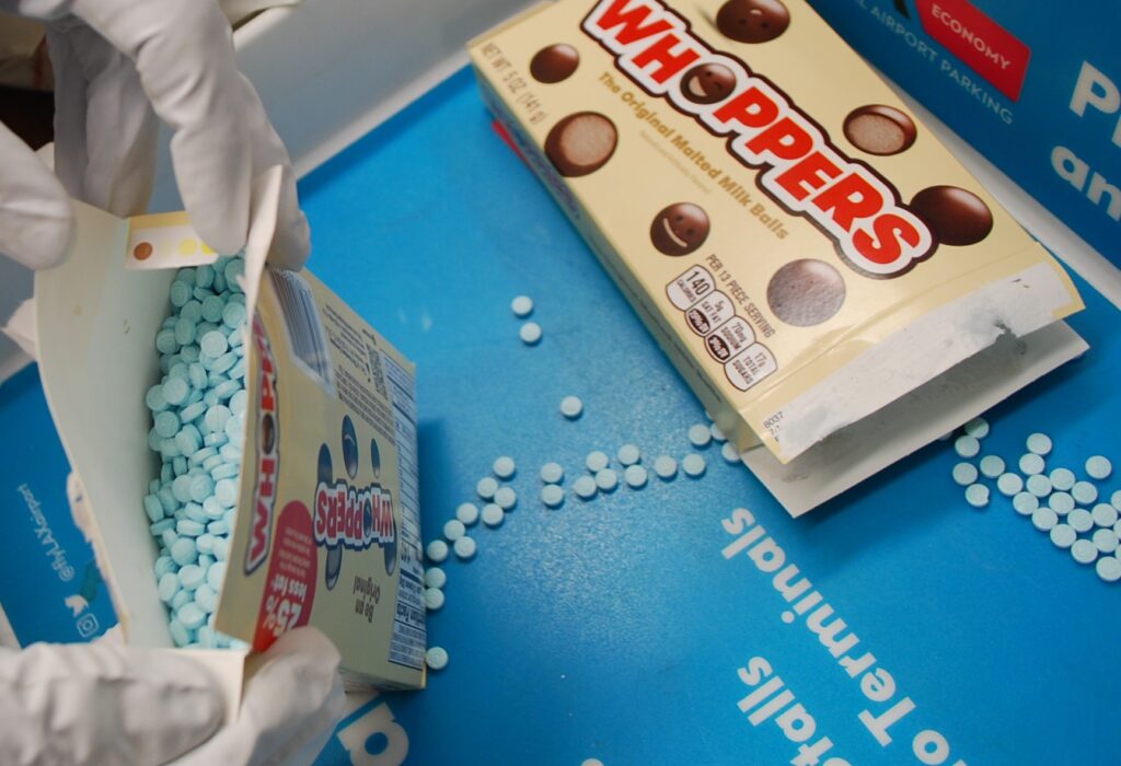 Box of candy open revealing small round pills. Instead of choclate candy that is depicted on the box.